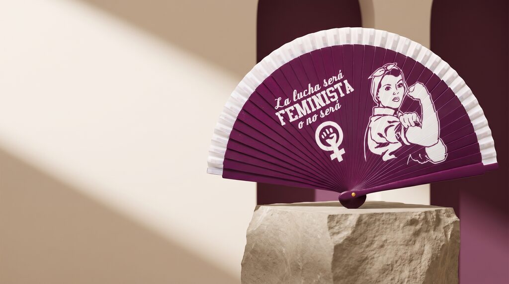 Abanico La Lucha Será Feminista sobre un pedestal de piedra: fondo violeta con el mensaje «La lucha será feminista o no será» y la figura de la mujer trabajadora